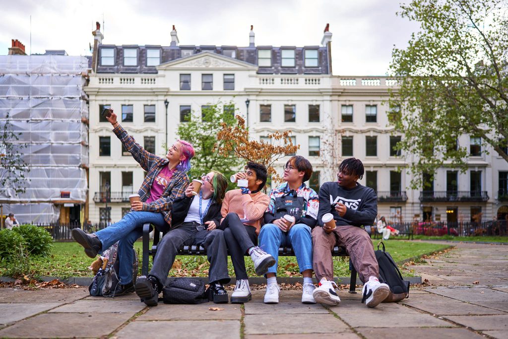 students sitting on bench taking selfie